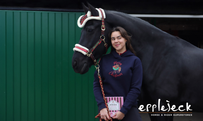 Meisje dat naast haard paard staat, meisje en paard hebben allebeide een kerstoutfit aan